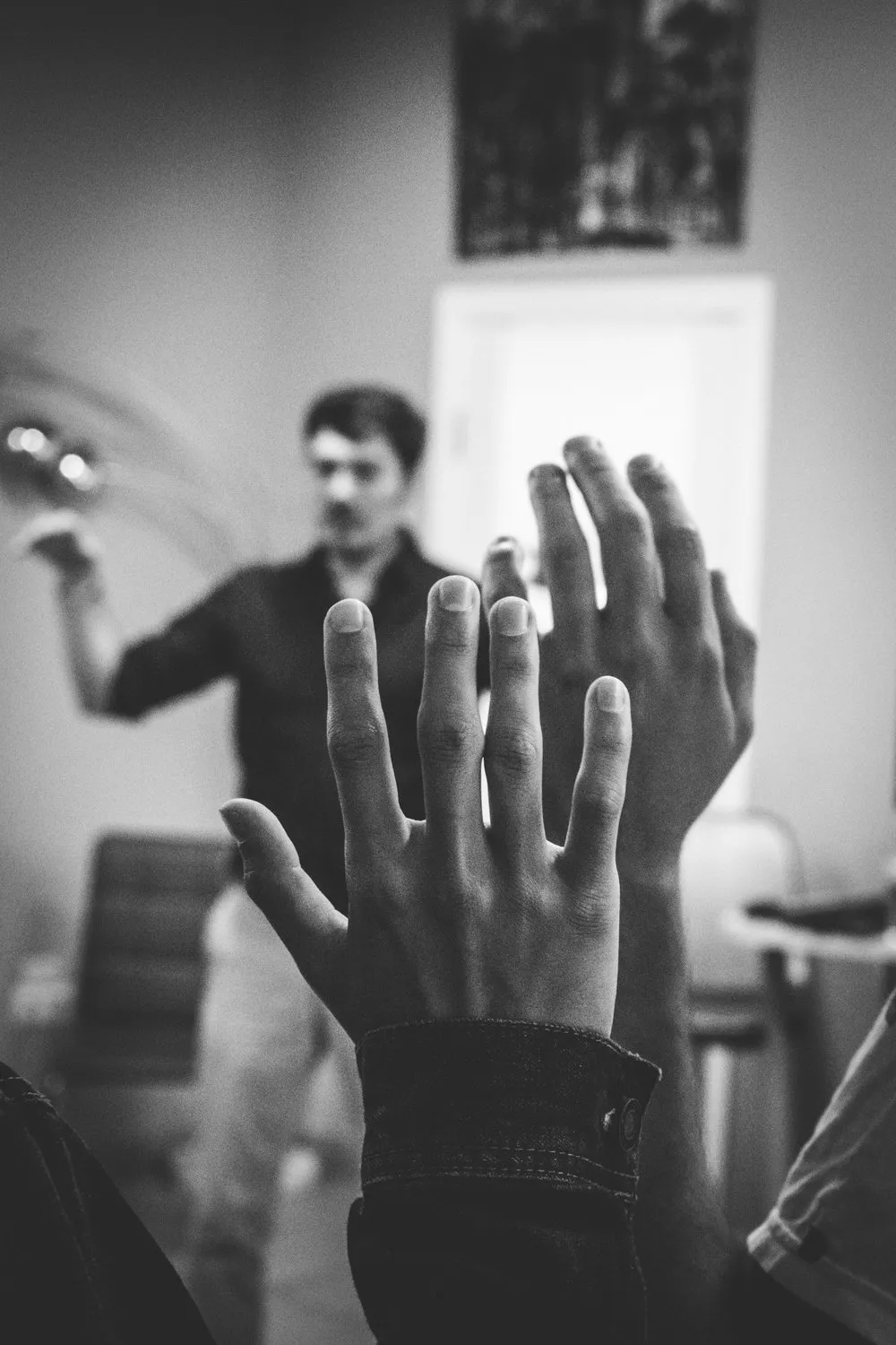 Hands raised in a room during a working session, one person standing at the front.